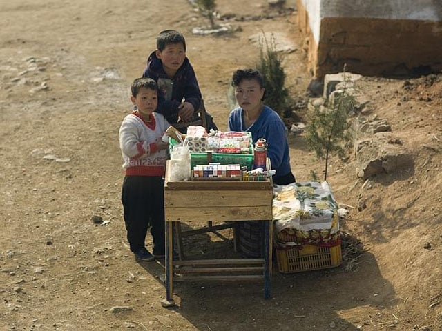 A family selling cigarettes and candy on the side of the road.
