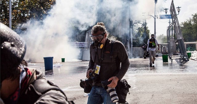 Freelance photographer and FFR member Bill Kotsatos is seen during clashes between anti-government protestors and riot police, 01 December 2013, in central Bangkok, Thailand. (© Adam Gnych)