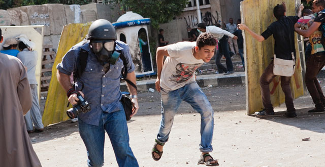 Protestors flee and hide behind makeshift shields from rocks being thrown by police in front of the US Embassy, Cairo, Egypt, 14 September, 2012, on the fourth day of protests in response to an Anti-Islamic film released in the United States. (© Amanda Mustard)