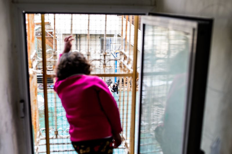 Girl from the Palestinian family looking outside through the barb wire window where the Jewish kids play.