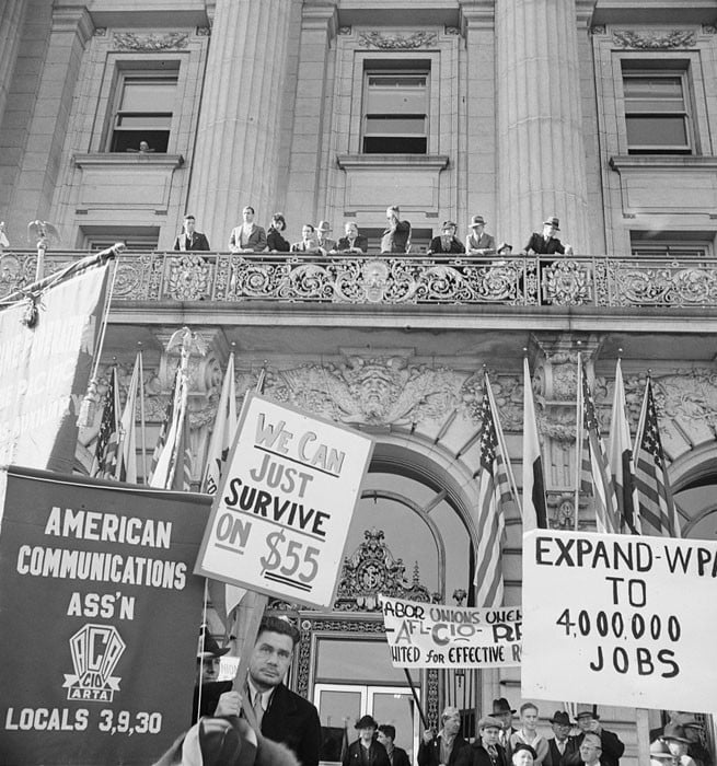 City officials hear the speeches made at mass meeting of Works Progress Administration (WPA) workers protesting cut in relief appropriation. In front of city hall, San Francisco, California. February 1939.