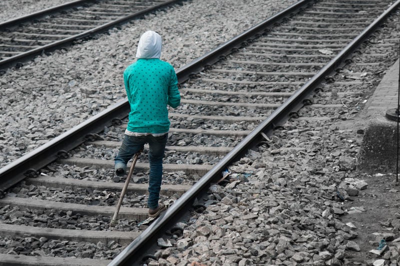 An amputee makes his way along the tracks outside Guwahati Junction, Assam