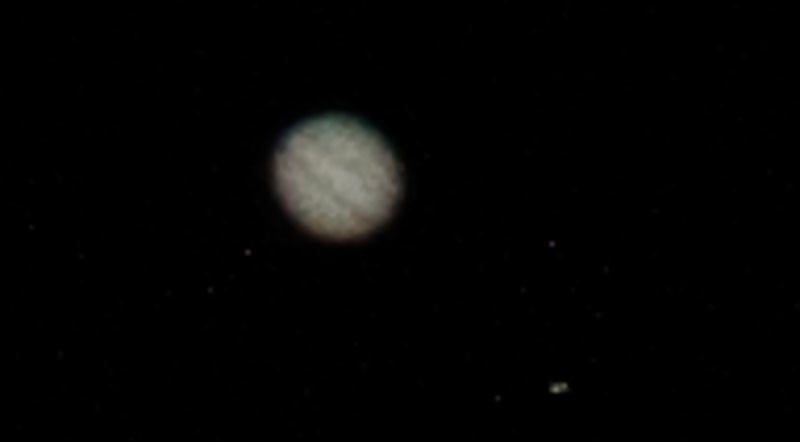A slightly enhanced and very much cropped segment of the prior image. Cloud bands in the atmosphere are visible and the Great Red Spot is also just about visible - if the disc of Jupiter is a clock face, the spot is at about 9 o'clock. Color information is lacking because it's so faint. You can also see one of the moons at bottom right (the other faint specks are just stars)