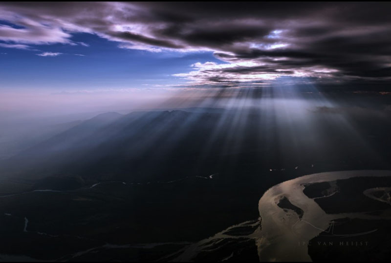 Sunlight streaming through clouds onto the state of Alaska.