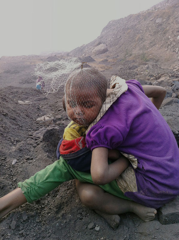 Children wait for their parents to return from work, both of whom are coal pickets inside a coal mine in Jharia.