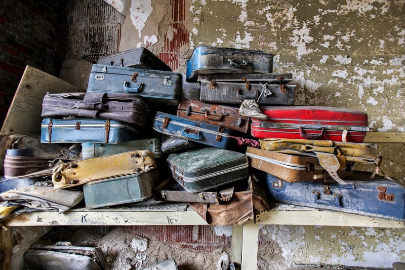 Patient luggage stacked in a top-floor room of an intake administration building. Patients would arrive with personal belongings in the hopes they could enjoy a piece of 'home' while institutionalized; however these belongings would simply be placed into storage. 