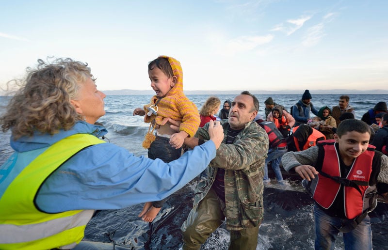 Volunteers carry a child ashore on a beach near Molyvos, on the Greek island of Lesbos, on October 30, 2015, after a group of refugees crossed the Aegean Sea from Turkey in a small overcrowded boat provided by Turkish traffickers to whom the refugees paid huge sums. The refugees were received in Greece by local and international volunteers, then proceeded on their way toward western Europe. Under "informed consent" rules, the volunteers would have to give their written permission for this to be used, and the parents or legal guardianw of the two children would also have to agree and sign a release. The photographer would have had to produce the forms for their signature while they were busy getting out of cold wet clothes and into dry clothing and continuing their journey. Photo by Paul Jeffrey.