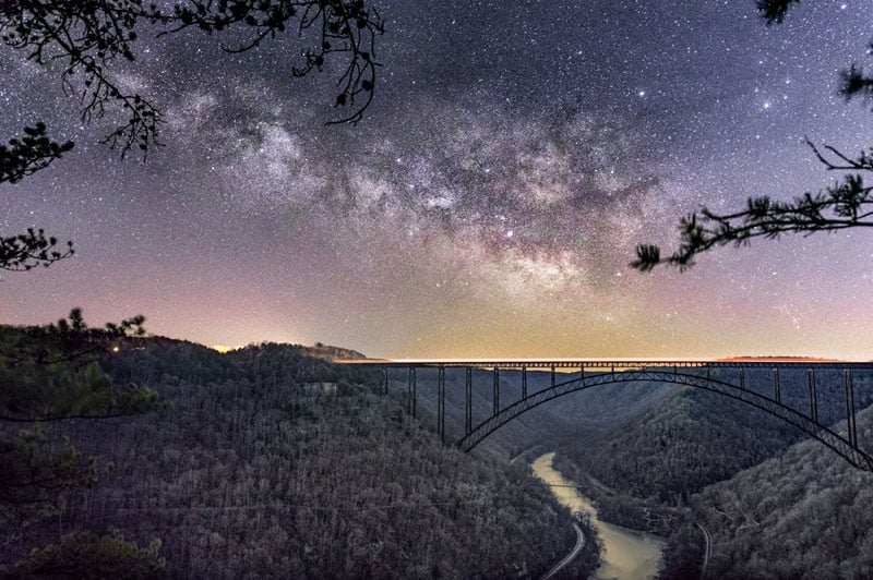Another angle on the New River Gorge Bridge. This time I used morning twilight to provide lighting of the landscape. The Milky Way was taken at 3 am, while the landscape was shot about 3 hours later, a bit before sunrise. Additionally, 12 foreground shots were stacked in order to reduce noise.  The time when astronomical twilight begins, or just before it ends is the best time for these shots because the result is not overly bright and blends well with the night sky.