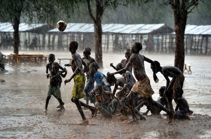 Children play football during an October 2012 rainstorm in the Doro refugee camp in South Sudan's Upper Nile State. More than 110,000 refugees had come to camps in Maban County from Sudan's Blue Nile region, where the Sudanese military was bombing civilian populations as part of its response to a local insurgency. Under "informed consent" rules that require prior approval, the photographer would have had to stop the boys from playing, have them find and identify their parents somewhere in the sprawling camp, explain the intricacies of "informed consent" and usage, get their signatures, and then return to photograph the game. That's a process that's allegedly designed to assure that the boys are not depicted in an undignified manner. Photo by Paul Jeffrey.