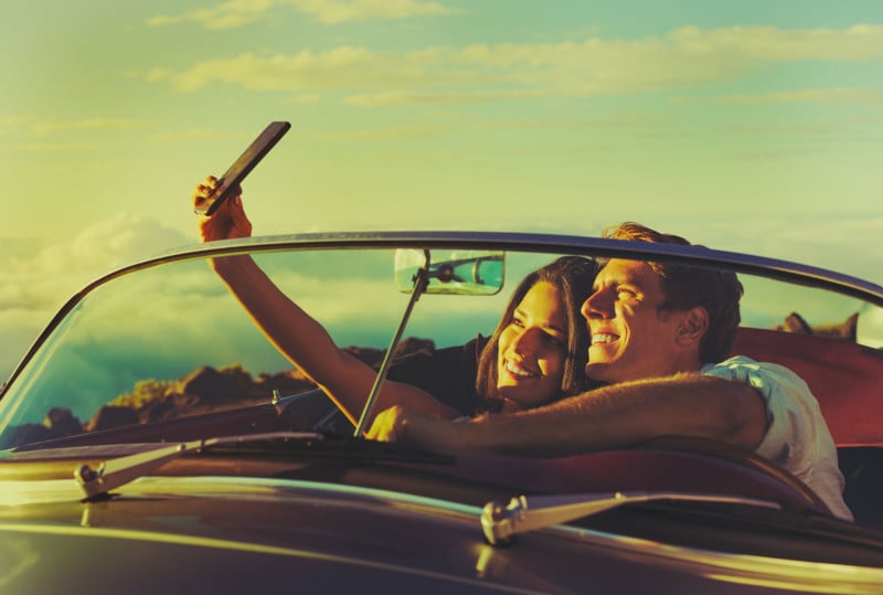 Romantic Young Couple Taking a Selfie in Classic Vintage Sports Car at Sunset