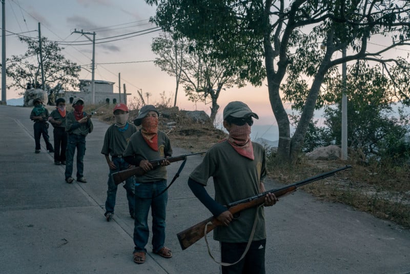 AYAHUALTEMPA, MEXICO - FEBRUARY 4: Alex (13), right, and other children stand during a Regional Coordinator of Community Authorities (CRAC-PF) community police force gun training presentation in the town of Ayahualtempa, Guerrero state, Mexico. Alex had to stop attending high school in the neighbor town of Hueycantenango due to the presence of drug cartel Los Ardillos. He then joined the communities police along his father. © Luis Antonio Rojas