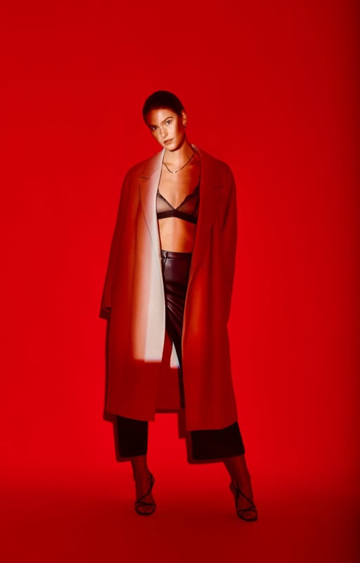 A woman posing in a fashion photo against a red background