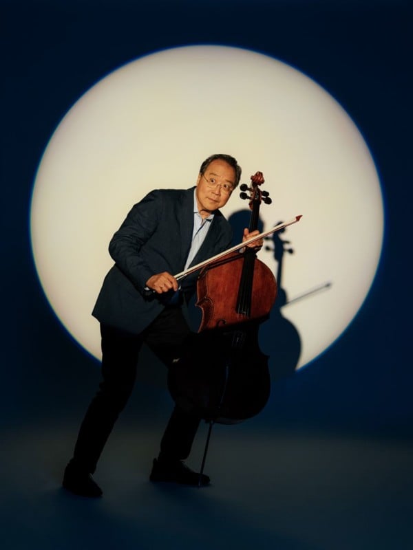 Cellist Yo-Yo Ma illuminated by a spotlight while holding a cello