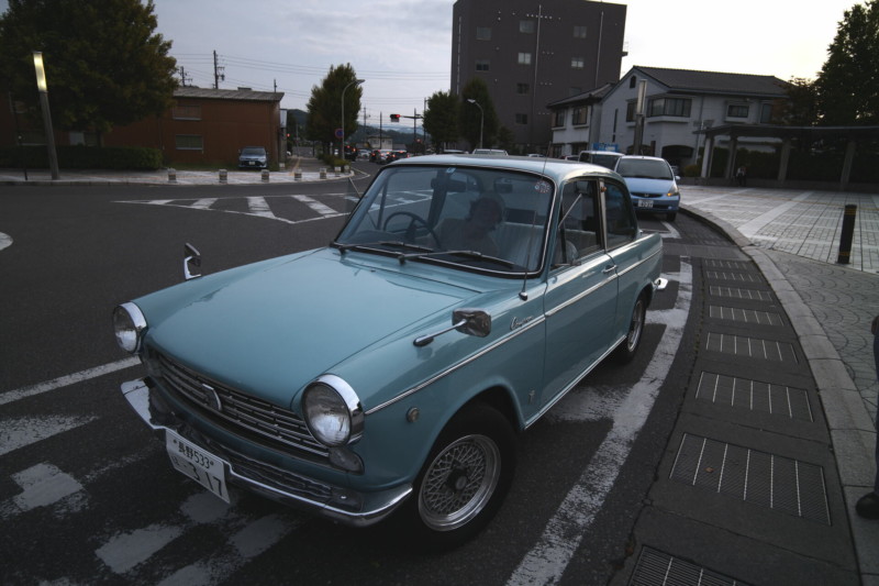 A blue car on the edge of a curved road