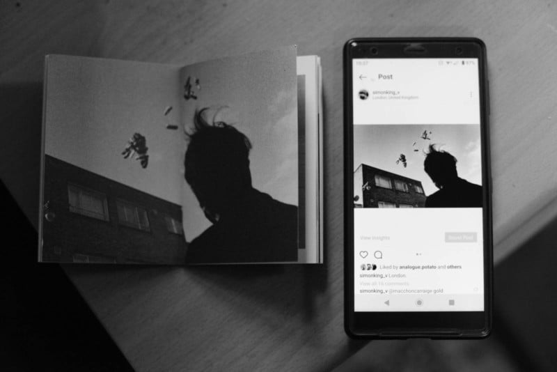 A photo book and smartphone both showing the same photo of a silhouetted man
