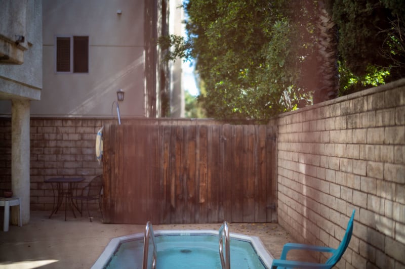 A photo of a backyard with a pool and chairs