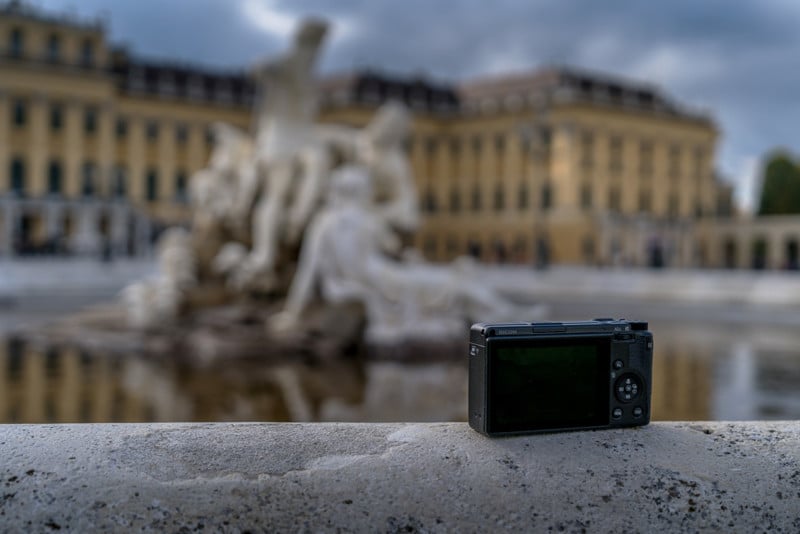 A Ricoh GR IIIx on the edge of a fountain in the city.