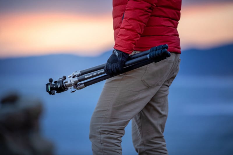 A person carrying a tripod outdoors