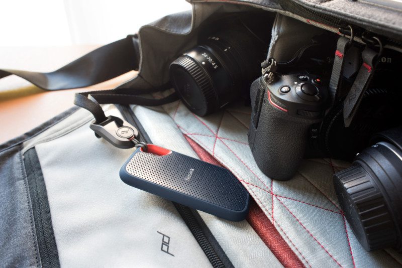 An external hard drive in a camera bag next to camera gear