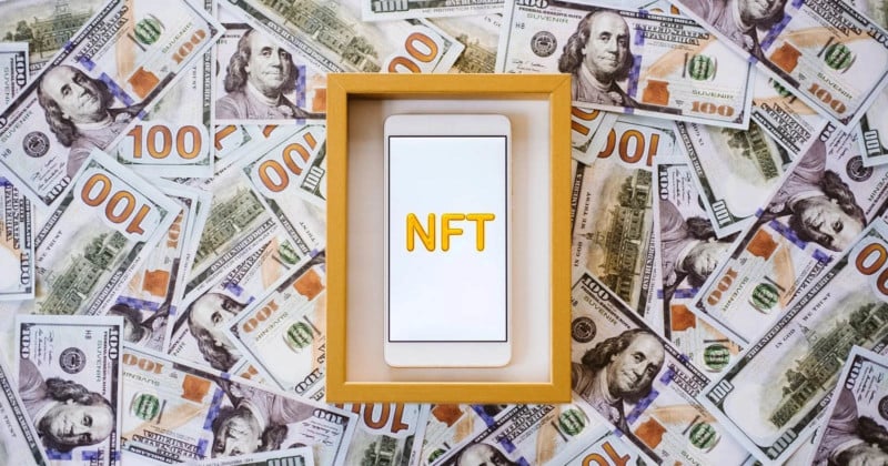 A photo of a smartphone with the words NFT in a frame on a background of bank notes