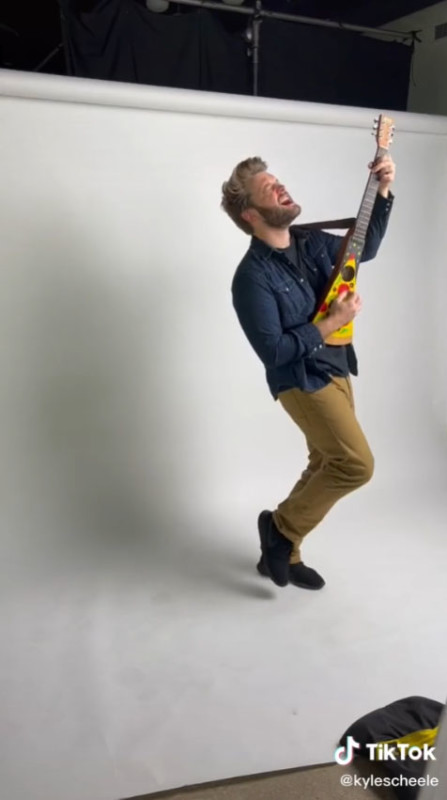 A man posing for a photo shoo with a pizza guitar