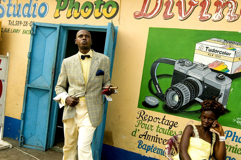 The Market Photo Workshop, 2007-8. Lalhande, 21, with his cigar, in front of a photo studio in Brazzaville © Daniele Tamagni