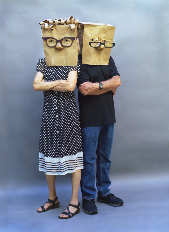Two people wearing paper bags with faces on their heads