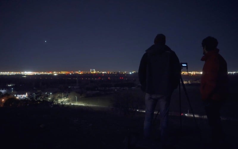 A man standing with a camera for a night photo of Madrid