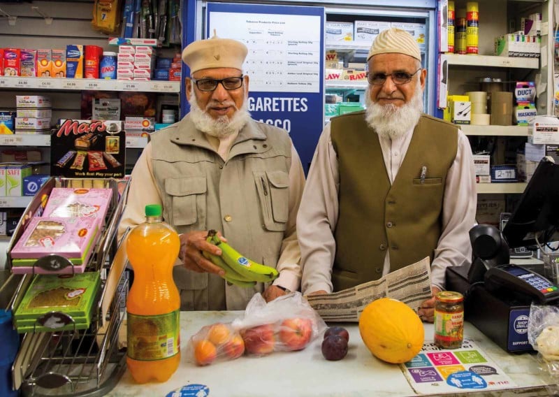 Two older men behind the counter of a store