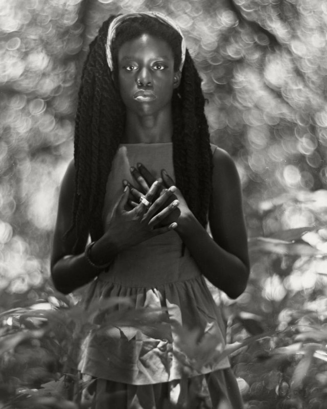 A black-and-white shallow depth of field photo of a woman standing outdoors