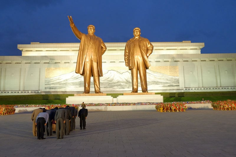 North Koreans pay respects to monumental statues of Kim Il-sung (left) and Kim Jong-il (right) at the Mansudae Grand Monument, Pyongyang. The background mosaic depicts Mount Paektu, the birthplace of Kim Jong-il according to local lore and a site of almost mystical significance for North Koreans. Pyongyang residents visit the monument on national holidays and special occasions such as weddings. Visitors who come from the provinces will make a point of seeing it at least once, in many cases laying flowers at the feet of the former leaders. © Fabian Muir/Courtesy Head On Photo festival