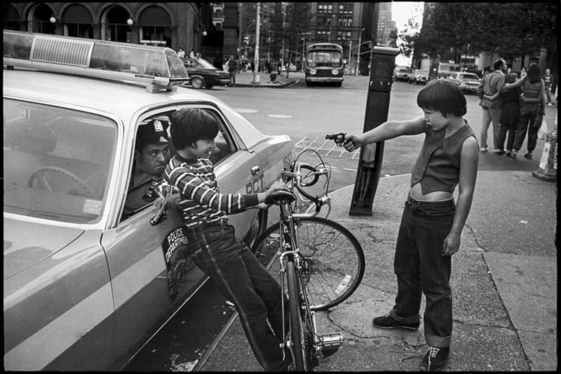 Kids playing with guns in front of police car