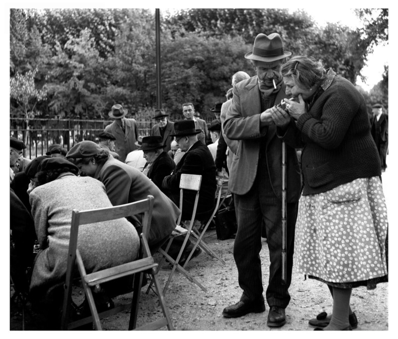 A photo of a man helping a woman light a cigarette by Sabine Weiss