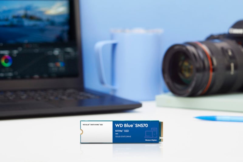 A SSD drive on a desk with a camera in the background