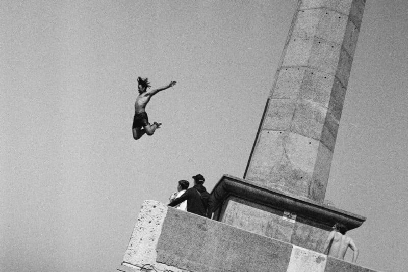 A black-and-white photo of a man jumping off a structure