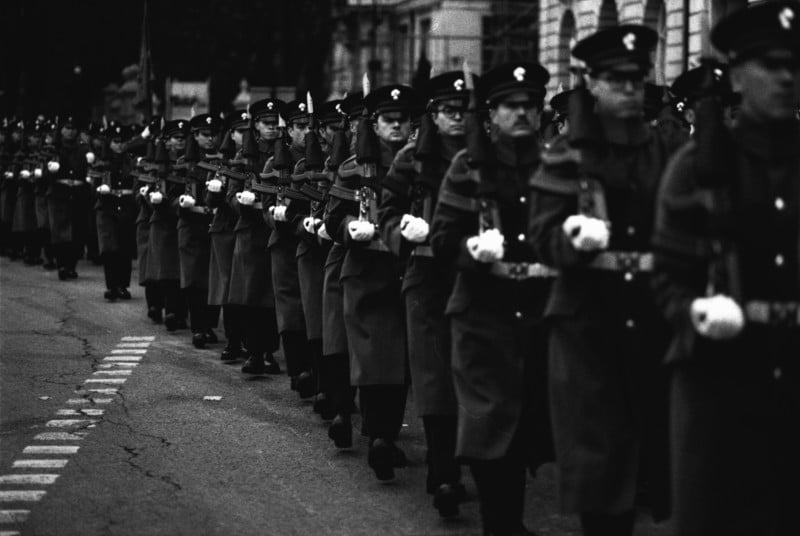 A march of uniformed soldiers holding rifles