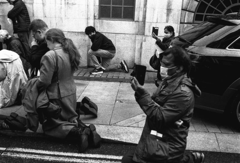 People kneeling in a street and shooting smartphone photos