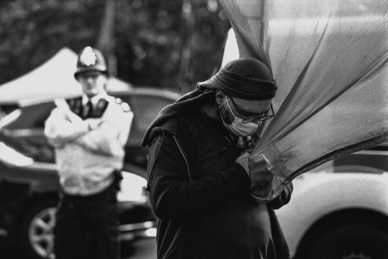 A policeman watching a masked protestor