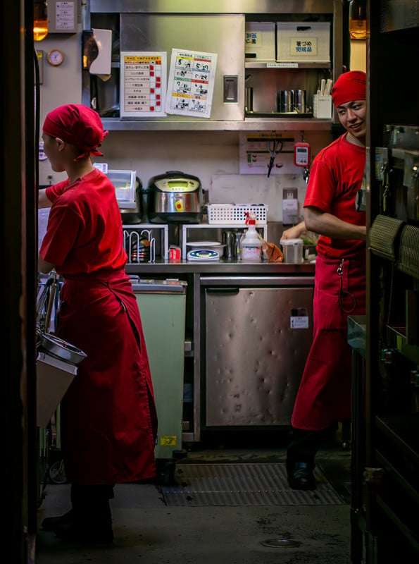 Two restaurant workers inside the open doors of a restaurant