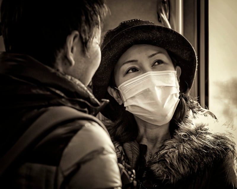 A woman wearing a mask and standing in front of a man