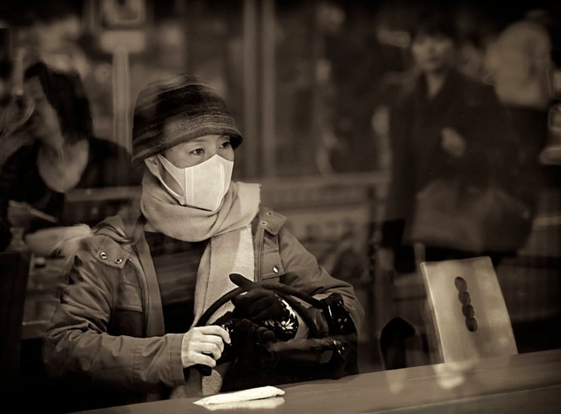 A woman behind reflections in a window