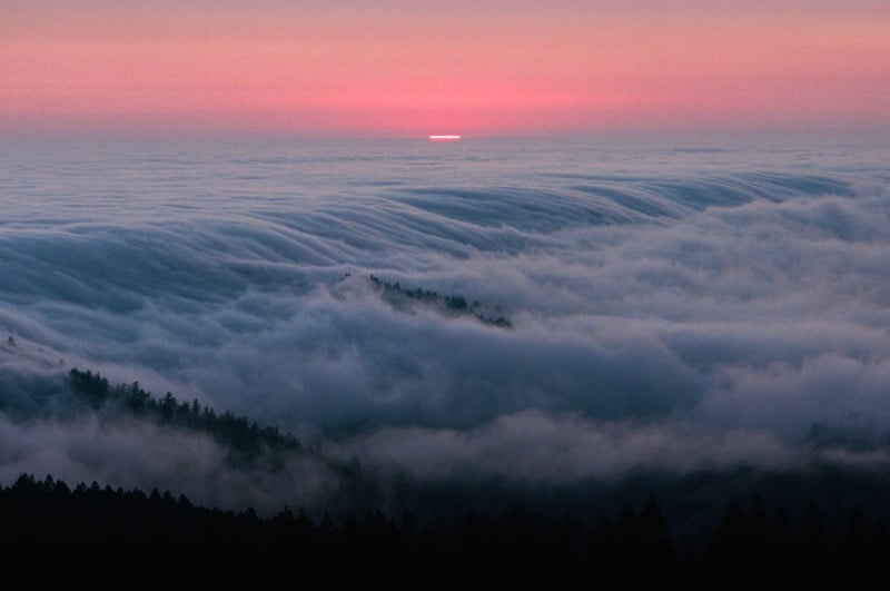 Fog rolling through a valley at sunrise or sunset