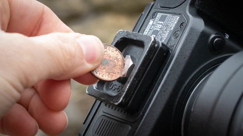 Person screwing on a tripod footplate with a penny