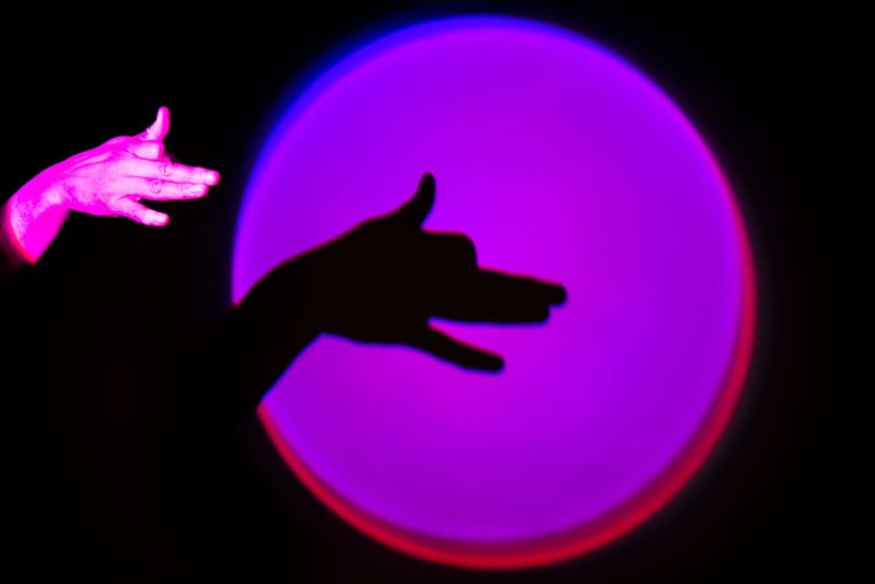 A hand gesture with a purple light behind it