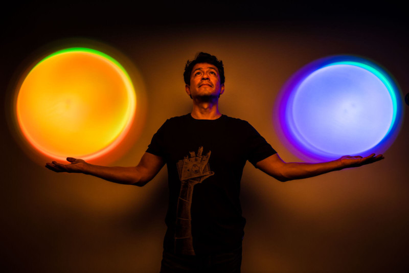 A man with two colorful round lights shining above his hands