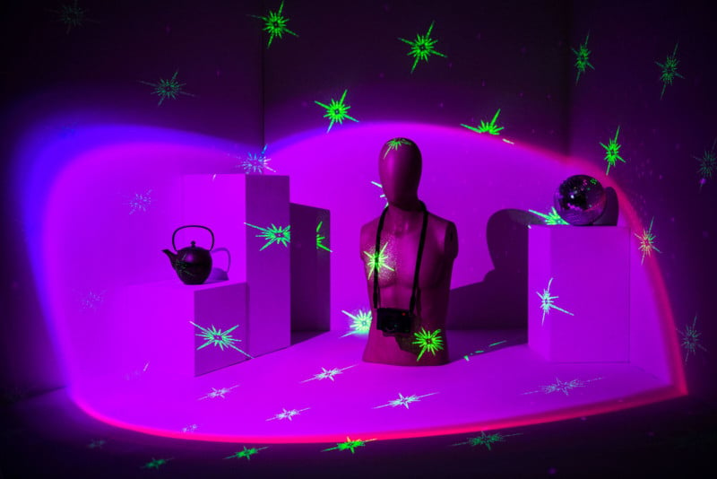 A mannequin illuminated with pink light and green projected symbols