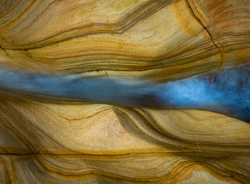 The tide sweeps through a channel in coastal sandstone