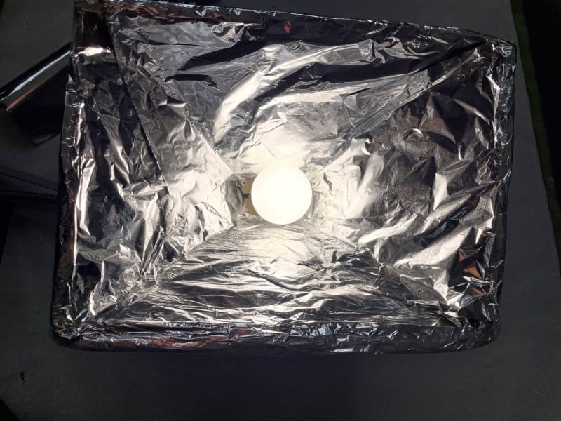 A foil-lined DIY softbox with a light bulb inside