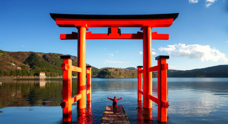 A person posing under the red torii gate of the Hakone Shrine