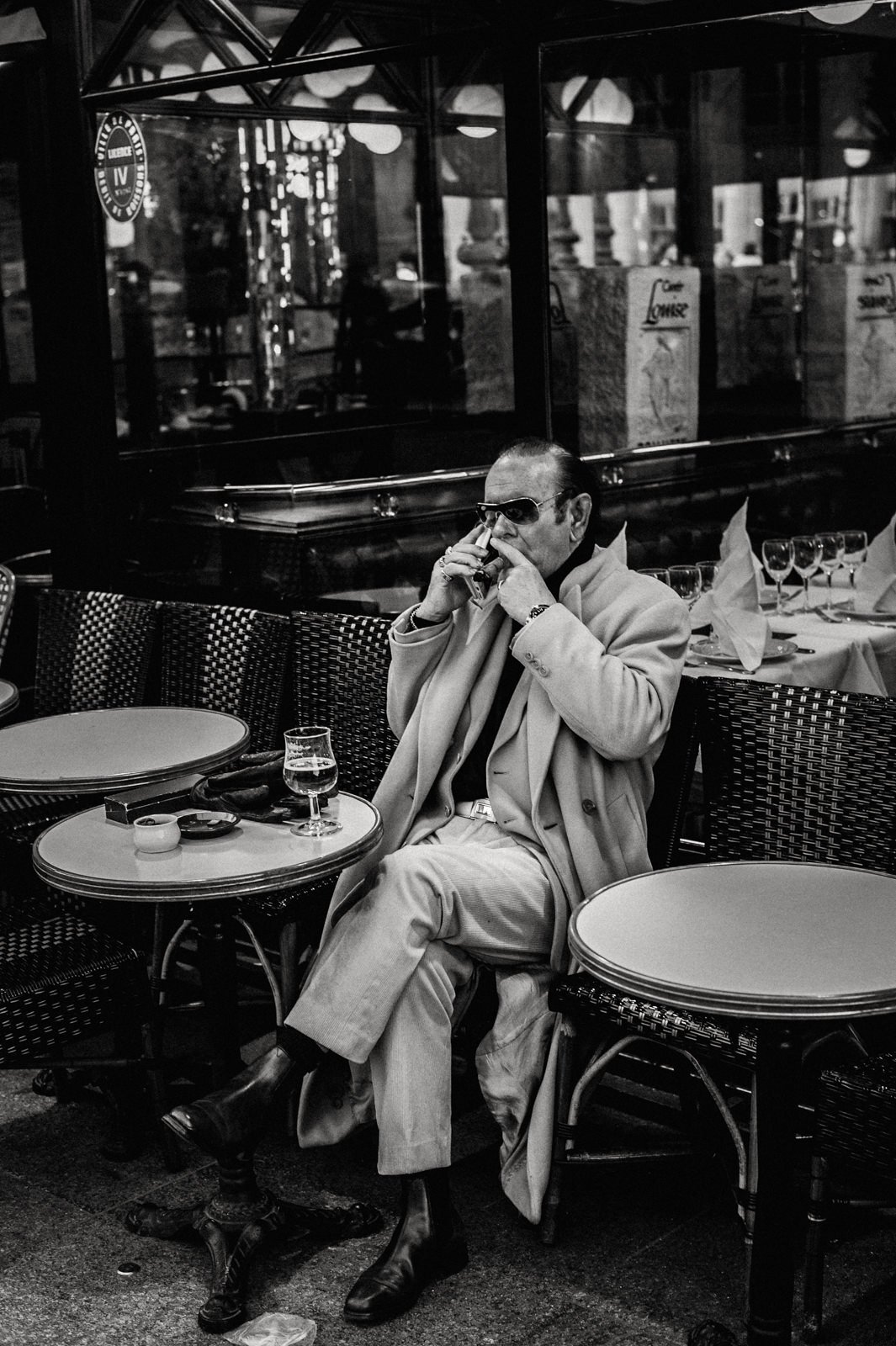 A Parisian man smoking and having a drink in a cafe